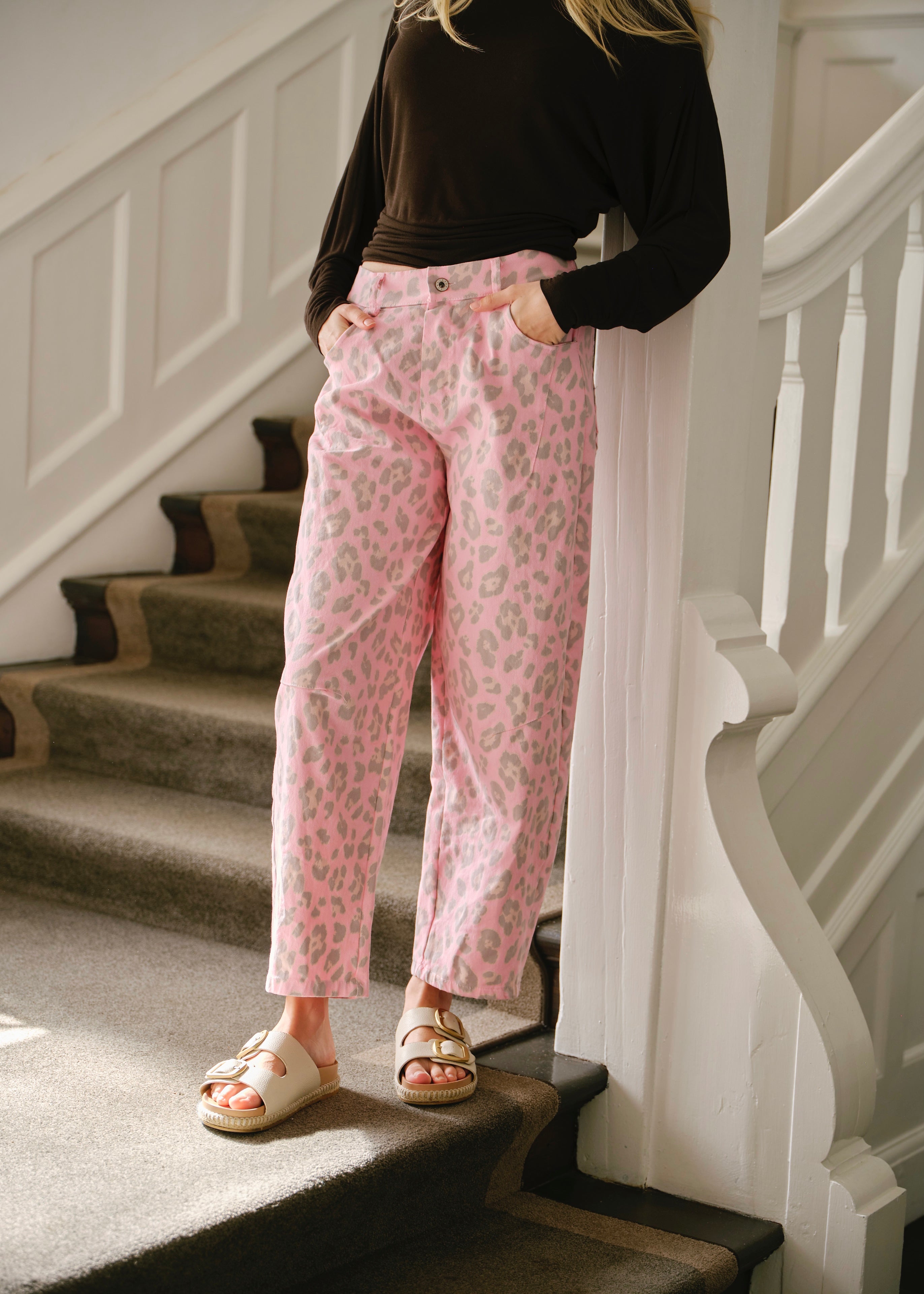 Woman wearing pink leopard print Italian barrel jeans with a black top