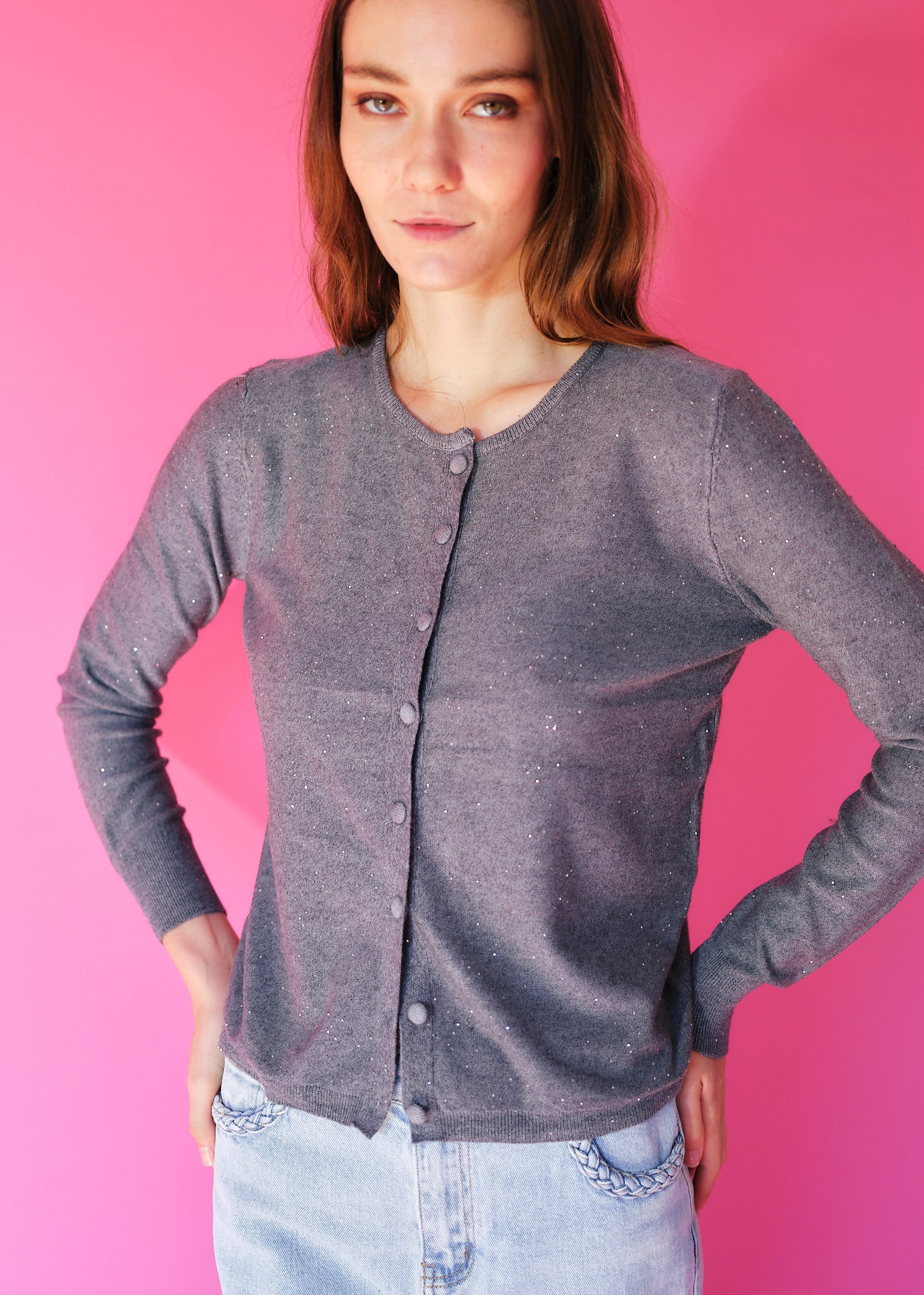 Woman wearing a gray cardigan against a pink background